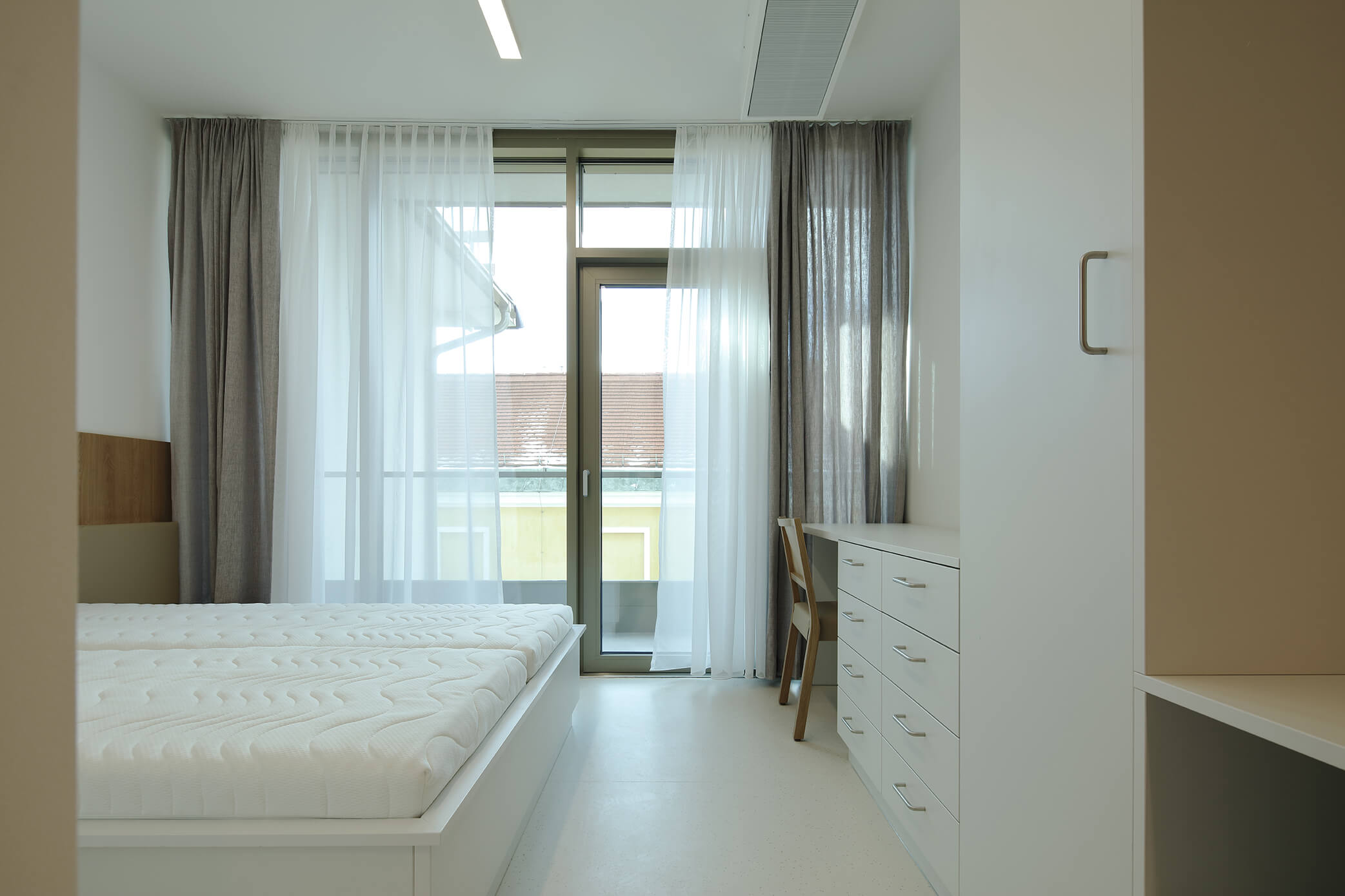 Pokoj s postelí, balkónem, stolem a skříní v nemocnici Elisabethinen